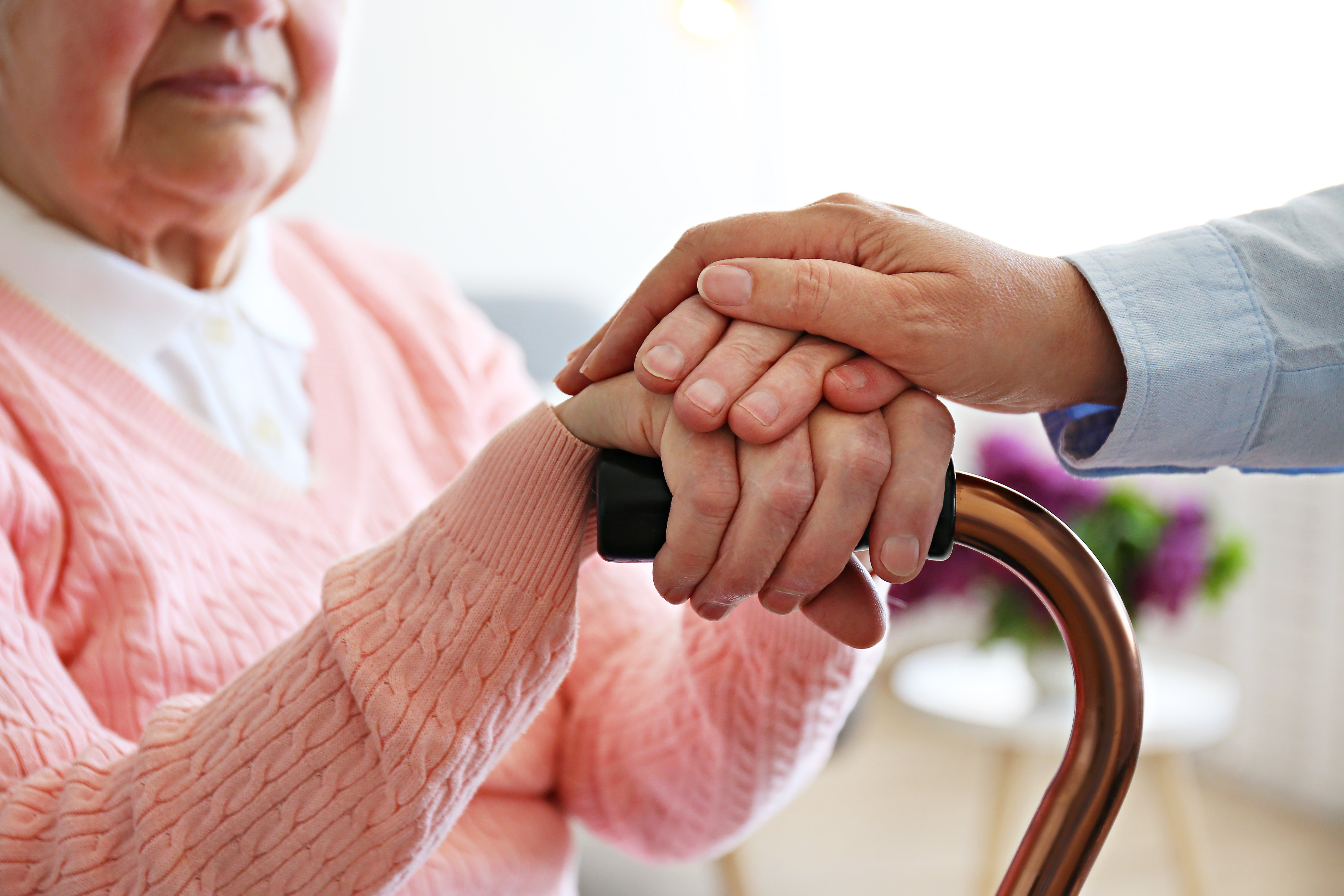 Old woman sitting in room of elderly care facility full of sun light.